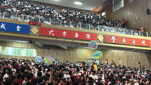 Photo 7. All freshmen reach out their hands to receive the large ball, symbolizing the passing on of tradition and hope.Image