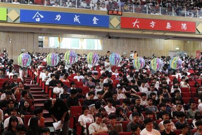 Photo 7. All freshmen reach out their hands to receive the large ball, symbolizing the passing on of tradition and hope.Image